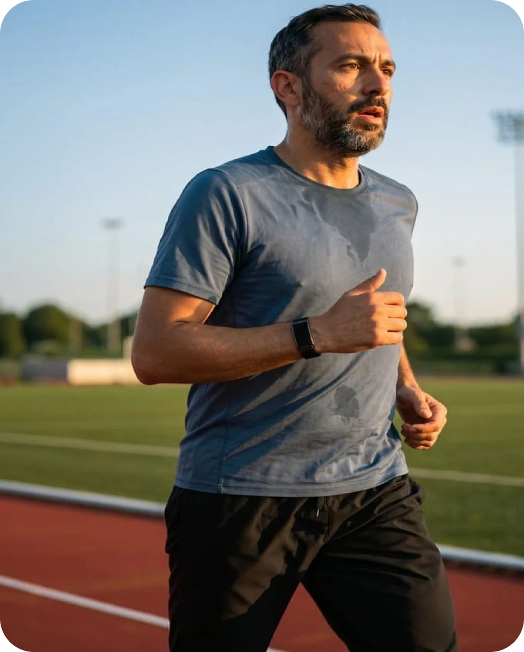 Man running on a track at golden hour wearing the HLTH Band